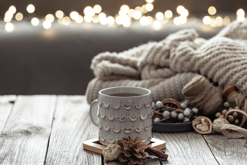 Cozy winter composition with a cup and decorative details with lights bokeh on the background.