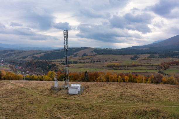 Cell tower near mountain settlement under gloomy sky