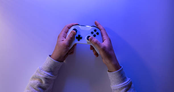 istock Male hands hold a gamepad on a blue background, copy space. 1361545325