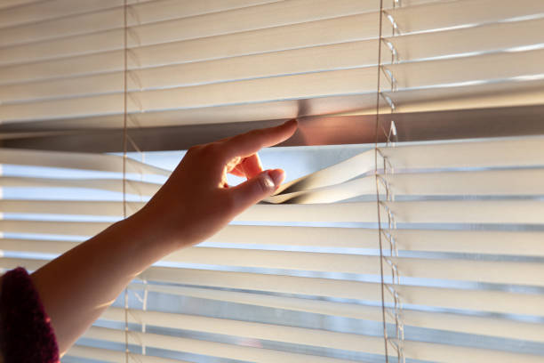 istock Woman's hand taking a peak through the window blinds. 1361546800