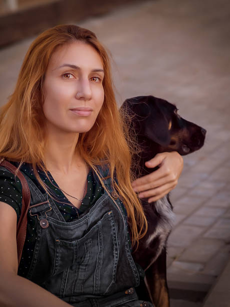 A fair-haired young woman lovingly hugs black-brown mongrel dog