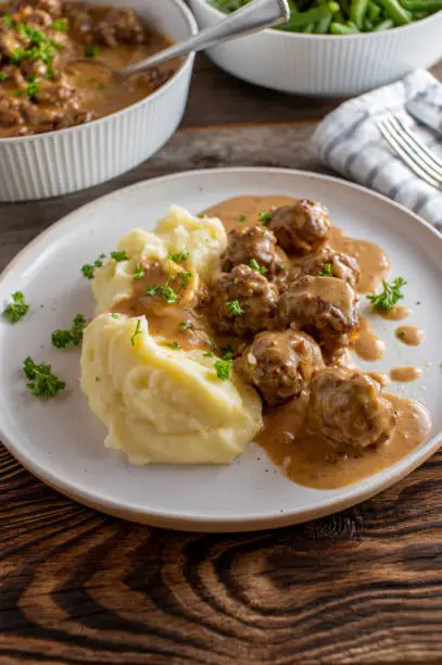Traditional fresh and homemade cooked Köttbullar, swedish meatballs in a delicious brown sauce. Served with mashed potatoes on a plate