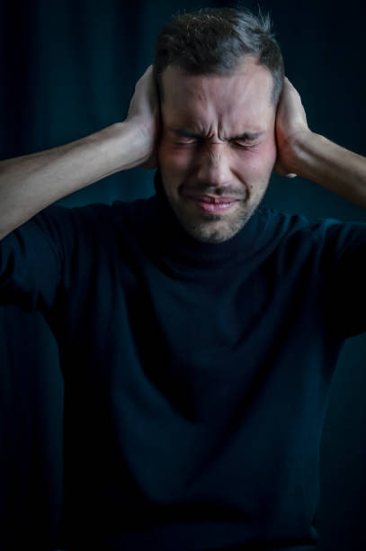portret młodego mężczyzny z rękami zakrywającymi uszy, aby nie słyszeć i zamkniętymi oczami, zaniepokojony hałasem - emotional stress irritation hands covering ears displeased zdjęcia i obrazy z banku zdjęć