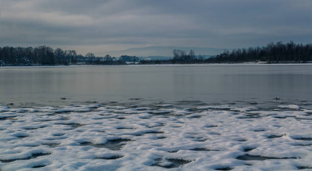 istock Snow on pond shore at cloudy overcast sky. Czech winter landscape 1361555519