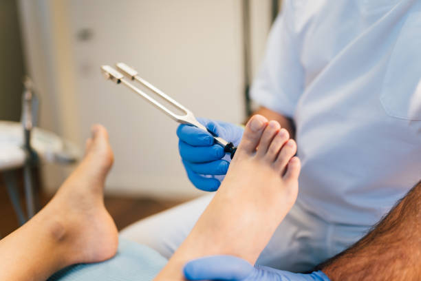 quiropodista explorando um pé paciente com diapason no centro médico - podiatry human foot podiatrist surgery - fotografias e filmes do acervo