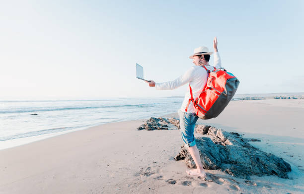 digital nomad on the beach at sunset smiling happy to the camera of the laptop - backpack one mature man only only mature men one man only imagens e fotografias de stock