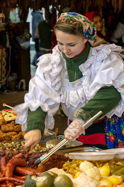 Young woman dressed in traditional costume from Maramures made specific food Timisoara: Young woman dressed in traditional costume from Maramures made specific food at street Christmas fair with traditional products. maramureș stock pictures, royalty-free photos & images