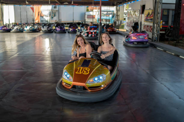 istock Two young girlfriends are laughing and shouting while riding a bumper car at amusement park 1361568650
