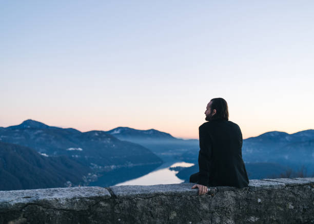 istock Businessman relaxes on mountain ridge at sunrise 1361568783