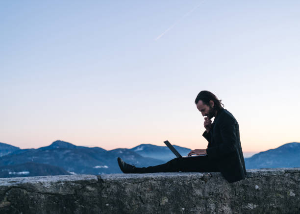 istock Businessman relaxes on mountain ridge at sunrise 1361568791