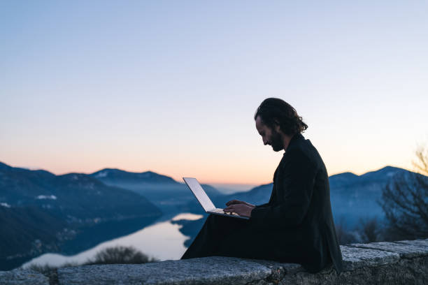 istock Businessman relaxes on mountain ridge at sunrise 1361570643