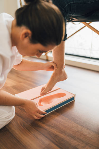 chiropodist taking the shape of a patient's foot with a foam mold for the manufacture of a special insole. - podiatrist podiatry pedicure chiropodist imagens e fotografias de stock