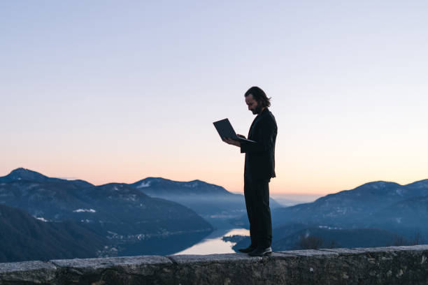 istock Businessman relaxes on mountain ridge at sunrise 1361572150