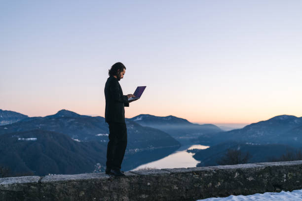 Businessman relaxes on mountain ridge at sunrise