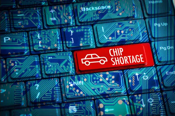 Photo of Chip Shortage or semiconductor automotive crisis concept with computer keyboard and motherboard circuits