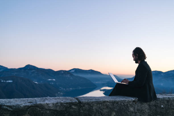 istock Businessman relaxes on mountain ridge at sunrise 1361573101