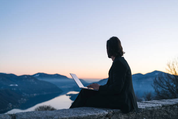 istock Businessman relaxes on mountain ridge at sunrise 1361573249