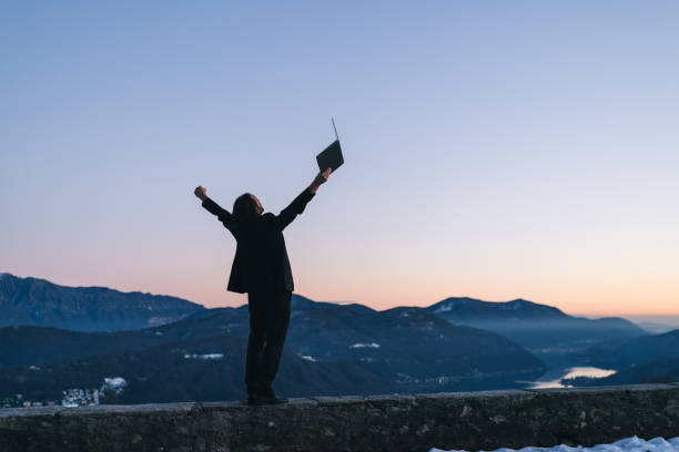 istock Businessman relaxes on mountain ridge at sunrise 1361574840