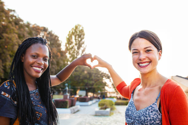 istock Two female friends making heart shape with their hands at sunset 1361578019