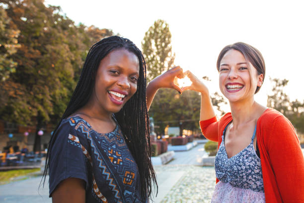 istock Two female friends making heart shape with their hands at sunset 1361578135