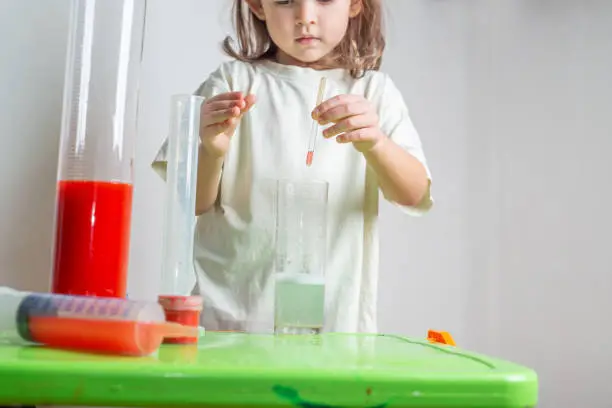 Photo of Child drips a colored liquid with a pipette into a test tube. A chemise experience at home. Homeschooling and distance education
