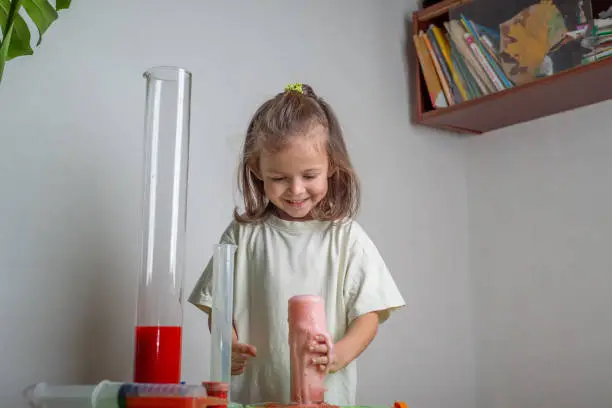 Photo of Cheerful child makes a volcano from soda and vinegar. A chemise experience at home. Homeschooling and distance education