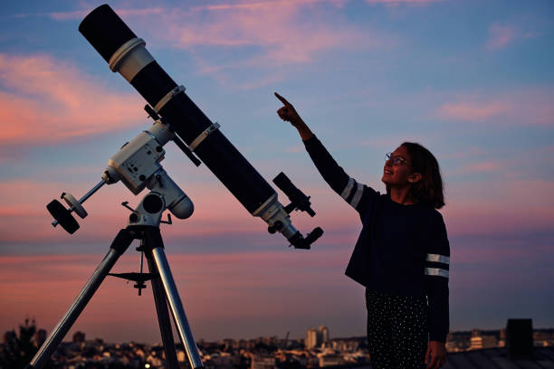 istock Girl with astronomical telescope stargazing under twilight sky. 1361579641