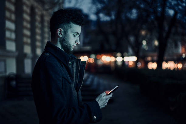 istock Handsome man using smartphone in night city street 1361583827