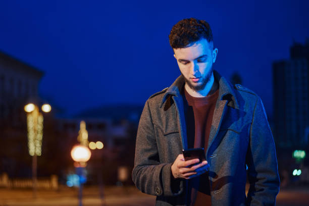 istock Handsome man using smartphone in night city street 1361583828
