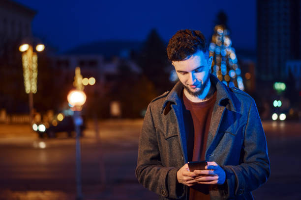 istock Handsome man using smartphone in night city street 1361583829