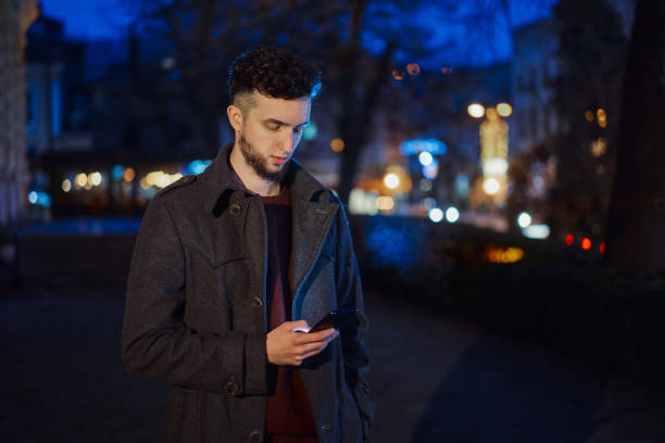 istock Handsome man using smartphone in night city street 1361583830
