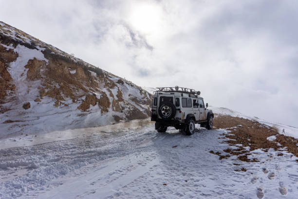 the white Land Rover is riding on snow at a foggy day in Anta stock photo
