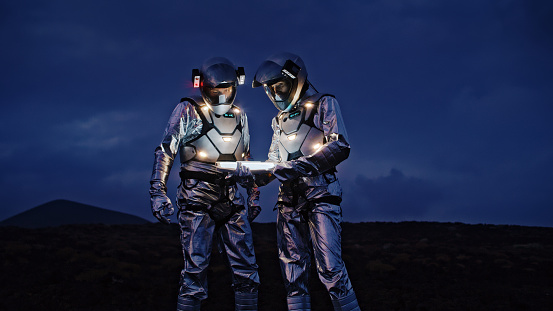 Selfie out of this world. Astronauts in futuristic suits taking photo and setting the light