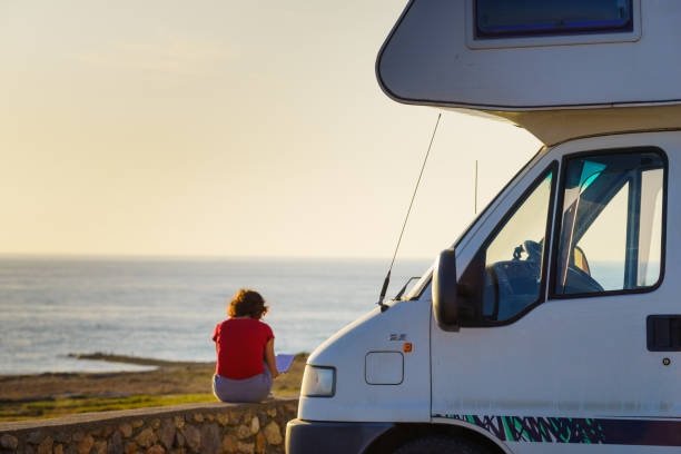 istock Caravan and woman read book on coast 1361592424