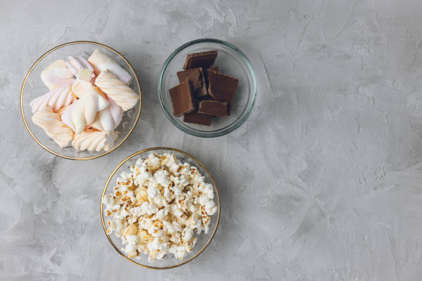 Popcorn, marshmallow, chocolate bar pieces in bowls. Ingredients for cooking, copy space