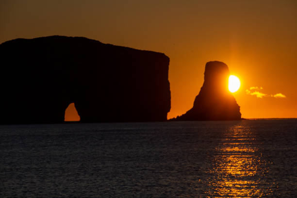 Sunset on Rocher Perce rock in Gaspe Peninsula, Quebec, Gaspesie region, Canada. Famous landmark in Saint Lawrence gulf water. stock photo