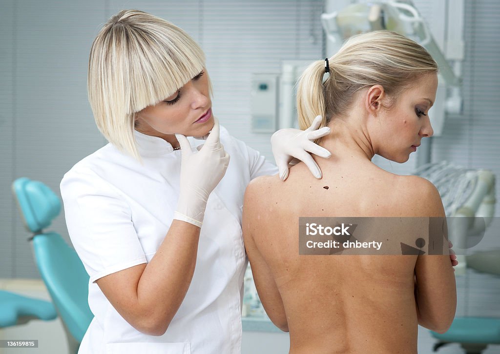 Lekarz Sprawdzanie kobieta skóry pacjenta - Zbiór zdjęć royalty-free (Atak ciałem - sport)