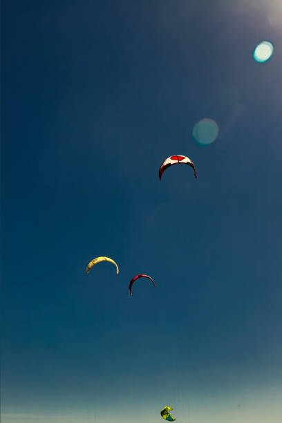 istock Four kitesurfing parachutes against blue sky and solar backlight 1361603276