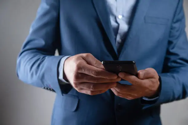 a man in a suit stands with a phone
