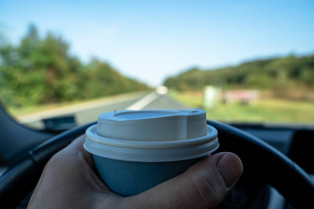 Men holds cardboard coffee cup in hand while he is taking a break in his car