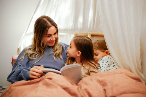 istock Mother and daughters reading book in bed before going to sleep 1361612102