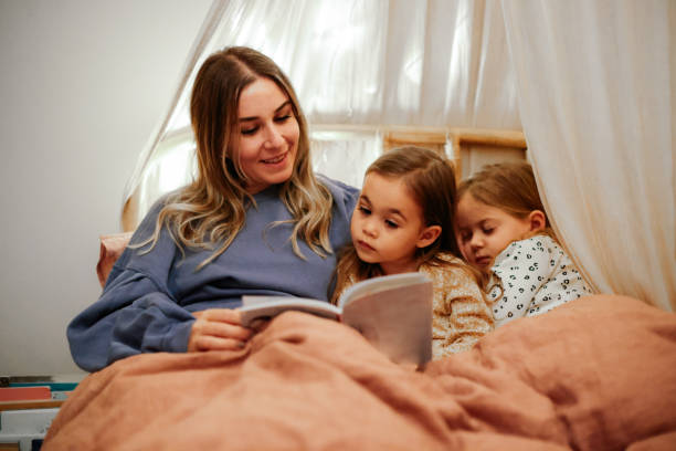 istock Mother and daughters reading book in bed before going to sleep 1361612189