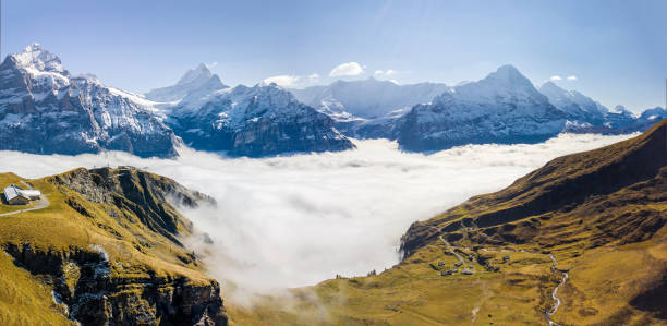 Aerial panorama of the First peak in Grindelwald with the famous Alps summits Aerial panorama of the First peak in Grindelwald with the famous Alps summit Wetterhorn, Schreckhorn and Eiger over the rising autumn fog Grindlewald stock pictures, royalty-free photos & images