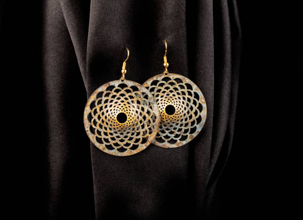 istock Round metal earrings hanging on black silk background 1361614416