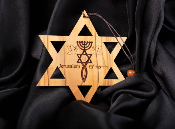 istock Wooden star of david on black silk background. 1361614430