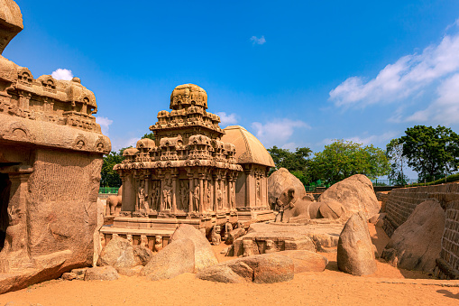 Image shows the Arjuna Ratha of the Pancha Rathas (also known as Pandava Rathas), a monument complex at Mahabalipuram or Mamallapuram, on the Coromandel Coast of the Bay of Bengal, in the state of Tamil Nadu, India. Behind it, a portion of the Draupadi Ratha can be seen. Dating from the late 7th century, it is attributed to the reigns of King Mahendravarman I and his son Narasimhavarman I (630-680 AD) of the Pallava Kingdom. The structures are without any precedence in Indian temple architecture and are carved out of a single granite rock each. Remarkably well preserved, they withstood the ravages of the Tsunamis of the 13th Century and 2004. They however display the effects of wind and sand erosion of over one thousand three hundred years. These are not temples as they are unfinished, and were never consecrated. They are part of the UNESCO World Heritage site at Mahabalipuram. Photo shot in the afternoon sunlight; horizontal format.