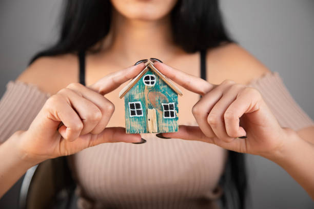 istock Young woman protecting the house in hands 1361617087