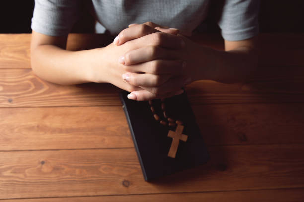 istock woman praying on book holding cross 1361617440