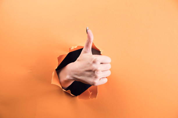 istock female hand showing thumb up on orange background 1361618584