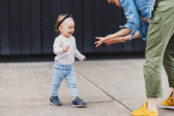 madre e figlia che giocano all'aperto - baby first steps autumn child foto e immagini stock